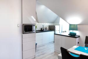 a white kitchen with white cabinets and a table at Turkus Holiday in Pobierowo