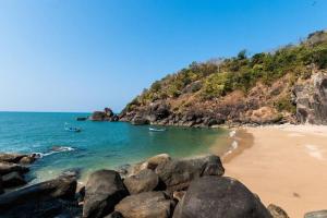 a beach with two boats in the water and rocks at Tulsi Authentic Homestay - Beach Village Goa in Canacona