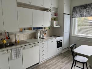 a white kitchen with white cabinets and a table at Apartment Huvilakatu in Kokkola +1 photo