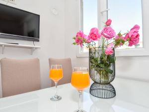 two glasses of orange juice and a vase with pink roses at Holiday Home Irma by Interhome in Sukošan