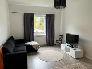 a living room with a black couch and a television at Apartment Huvilakatu in Kokkola
