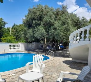 a swimming pool with two white chairs next to a white fence at Villa Dedin in Utjeha