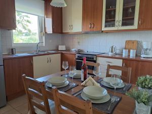a kitchen with a wooden table with plates and wine glasses at Maison Du Lac in Kanoni