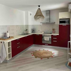 a kitchen with red cabinets and a rug on the floor at Appartement avec piscine in Calvi