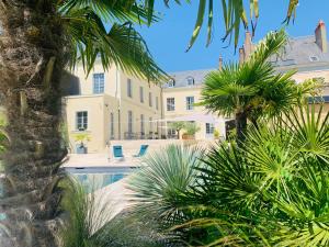 a large house with a swimming pool and palm trees at Les Chambres de La Varenne in La Flèche