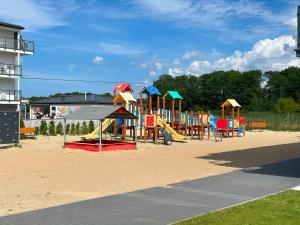 a playground with colorful play equipment on the sand at Modern & Spacious Apartments Baltin Blu by Noclegi Renters in Sarbinowo