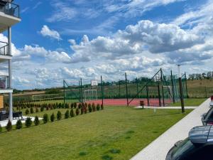 a tennis court in a grassy area with at Modern & Spacious Apartments Baltin Blu by Noclegi Renters in Sarbinowo