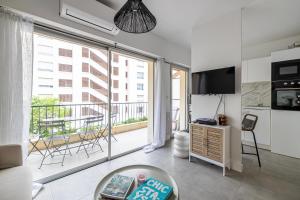 ein Wohnzimmer mit Blick auf einen Balkon in der Unterkunft CMG - Bel appartement avec balcon - 200m de la plage in Juan-les-Pins