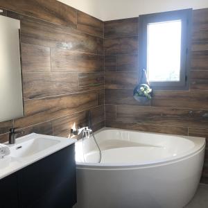 a bathroom with a white tub and a sink at La maison Adriel - Villa récente avec jardin et piscine in Saumane-de-Vaucluse