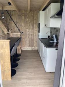 une cuisine avec des armoires blanches et des comptoirs noirs dans l'établissement Lange Heide, à Otterlo