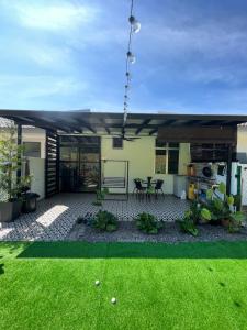 ein Haus mit einer Terrasse und einem Garten mit Gras in der Unterkunft Tun Teja Homestay Jasin Melaka in Jasin