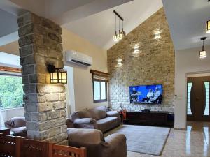 a living room with couches and a stone wall at Huge & Private Villa In Kibbutz Dafna in Dafna