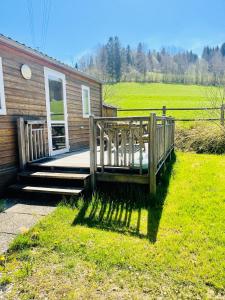 a house with a wooden porch and a grass field at Camping Le Miroir in Les Hôpitaux-Neufs