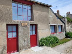 Cette maison ancienne est dotée de portes et de fenêtres rouges. dans l'établissement Gîte La Toue, à Saint-Dyé-sur-Loire