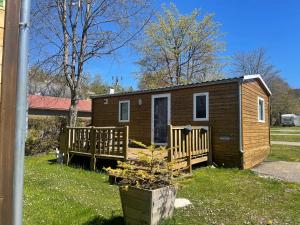 a tiny house with a porch and a deck at Camping Le Miroir in Les Hôpitaux-Neufs