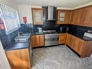 una cucina con armadi in legno e piano cottura. di No 51 - Spacious 3 Bed Home - Free Parking - Wi-Fi - Contractors a West Derby