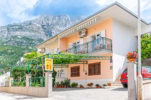 a house with a balcony and mountains in the background at Apartmani Roko in Baška Voda