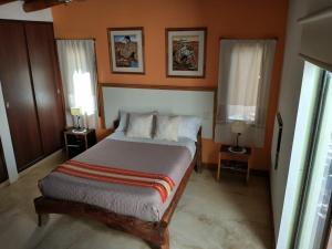 ein Schlafzimmer mit einem Bett mit zwei Tischen und zwei Fenstern in der Unterkunft Casa Santa Teresita in Cafayate