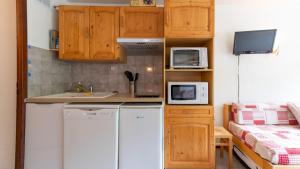 a small kitchen with wooden cabinets and a white refrigerator at Grand Morillon 116 - Appt pied des pistes - 5 pers in Morillon