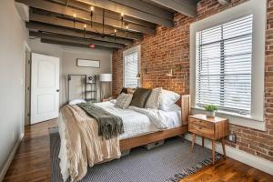 The Loft at 113 - Gateway to the North Texas Hill Country في Muenster: غرفة نوم بحائط من الطوب وسرير