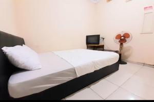 a bedroom with a bed and a tv in a room at SPOT ON 92599 Pondok Anggrek Syariah in Pekanbaru