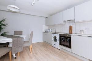 a white kitchen with a table and a washing machine at Relaxing 1BD Flat with a Roof Terrace - Portobello in Dublin