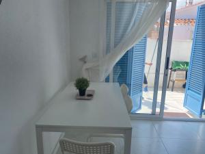 una mesa blanca con una maceta junto a una ventana en PETRA, en Denia