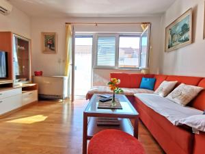 un soggiorno con divano rosso e tavolo di Apartment Tonka a Mlini