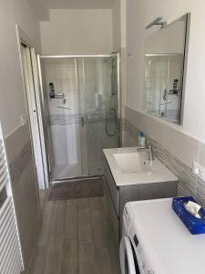 a bathroom with a shower and a sink and a washing machine at Punta TRE in Punta Marina +4 photos