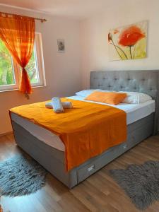 a bedroom with a bed with an orange blanket on it at Apartments Petrovic in Rogoznica