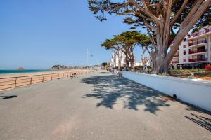 a sidewalk next to a beach with trees and a building at Coup de coeur pour un appartement en bord de mer à Pléneuf-Val-André in Pléneuf-Val-André