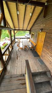 a large wooden porch of a cabin with a wooden door at Cabana Niki-Rum Haz in Bucsin
