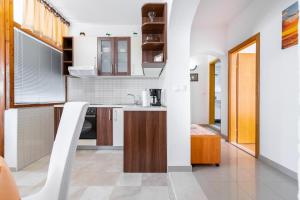 a kitchen with white walls and wooden cabinets at Apartmani Roko in Baška Voda