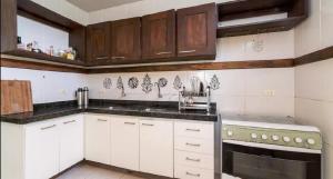 uma cozinha com armários brancos e bancadas pretas em Mar e Sol em Porto de Galinhas
