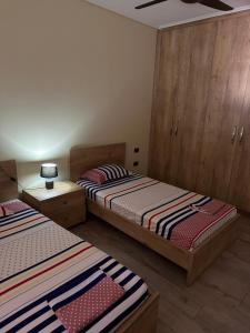 2 Betten in einem Zimmer mit Holzschränken in der Unterkunft Family Apartaments in Sarandë