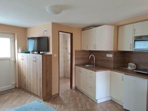 uma cozinha com armários brancos e uma televisão em Apartmán Store em Vracov