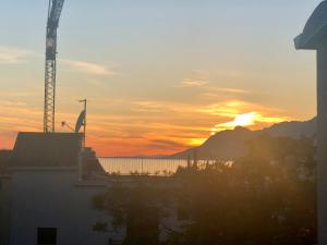 una puesta de sol con una grúa delante de un edificio en Villa Franko Baška Voda en Baška Voda