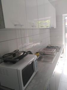 a white kitchen with a microwave and a stove at Casa Angy in Jurilovca