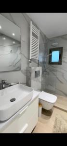 een badkamer met een wastafel, een toilet en een televisie bij Μοντέρνα εξοχική μονοκατοικία με ιδιωτική πισίνα! in Khalkoútsion