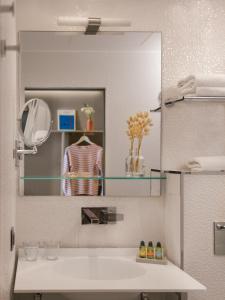 baño con espejo y lavabo blanco en Legend Hôtel Paris en París