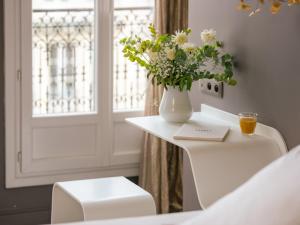 un vaso di fiori seduto su un tavolo bianco con una finestra di Legend Hôtel Paris a Parigi