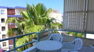 a balcony with a table and two chairs and a palm tree at Apartamentos Colon in Salou