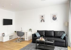 uma sala de estar com um sofá preto e uma cadeira em Moderne Apartments im Herzen der Stadt I private Tiefgarage mit Ladesäulen I home2share em Ibbenbüren