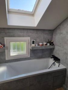 uma banheira branca na casa de banho com uma clarabóia em Charmante maison proche de Paris em Sainte-Geneviève-des-Bois