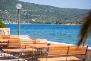 eine Gruppe von Tischen und Stühlen neben einem Wasserkörper in der Unterkunft Mamin san in Cres