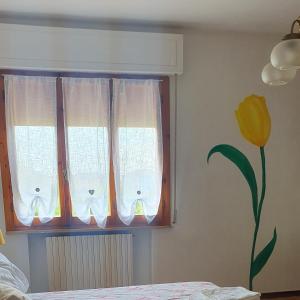 a window with white curtains and a yellow flower at Latte e Menta in Lamporecchio