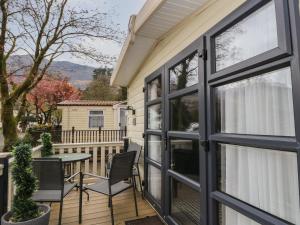 a patio with a table and chairs and a window at Loch Lomond Holiday Home in Arrochar