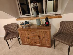 a wooden cabinet with two chairs and a window at Ystafell Gelert Room in Beddgelert