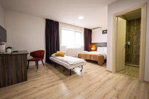 a hotel room with a bedroom with a bed and a chair at Bliss Inn Tunari in Tunari
