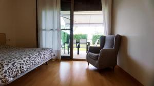 Mirador del Delta في Camarles: غرفة نوم بسرير وكرسي وباب زجاجي منزلق